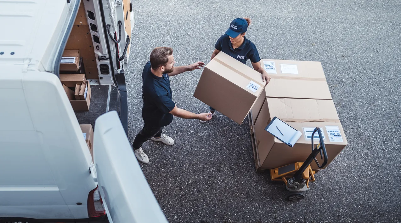 Two logistics workers handle packages for delivery.