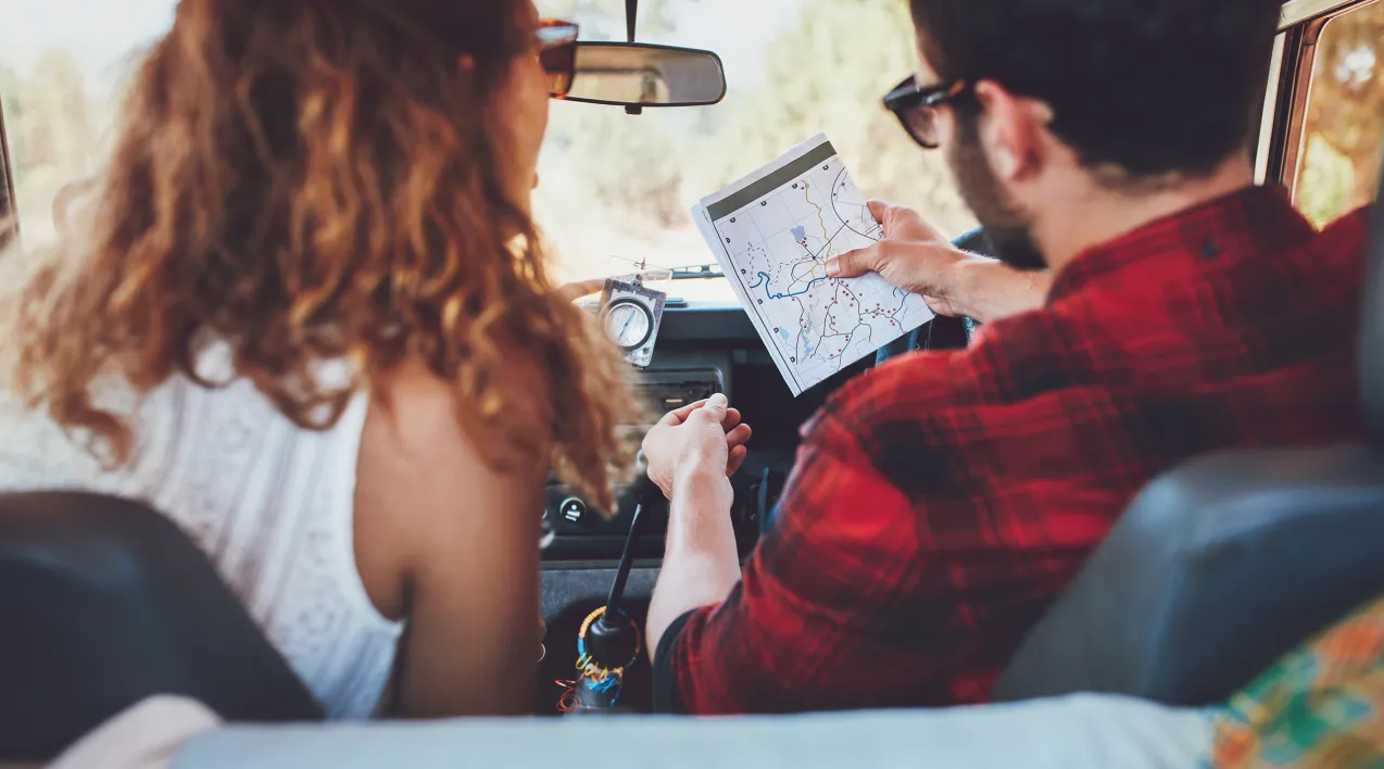 A couple in a car review a map.